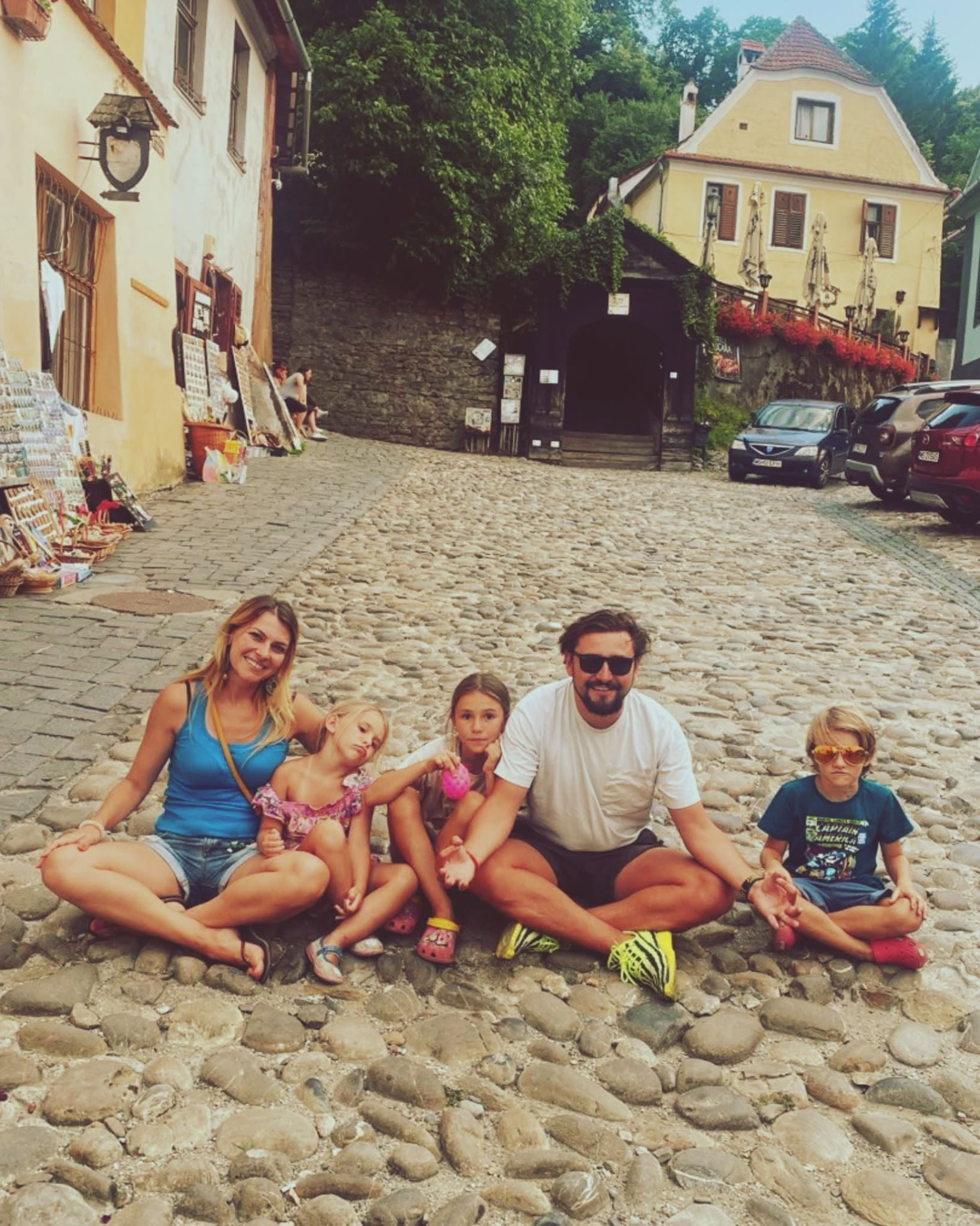 Ірина Зарецька-Котруце з родиною: мама, тато й трійко дітей сидять на бруківці старовинного європейського міста